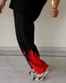 Side view of Red Fire Flame Kick Straight Baggy Track Pant by The Drip Soul showing detailed red flame graphic and relaxed silhouette.