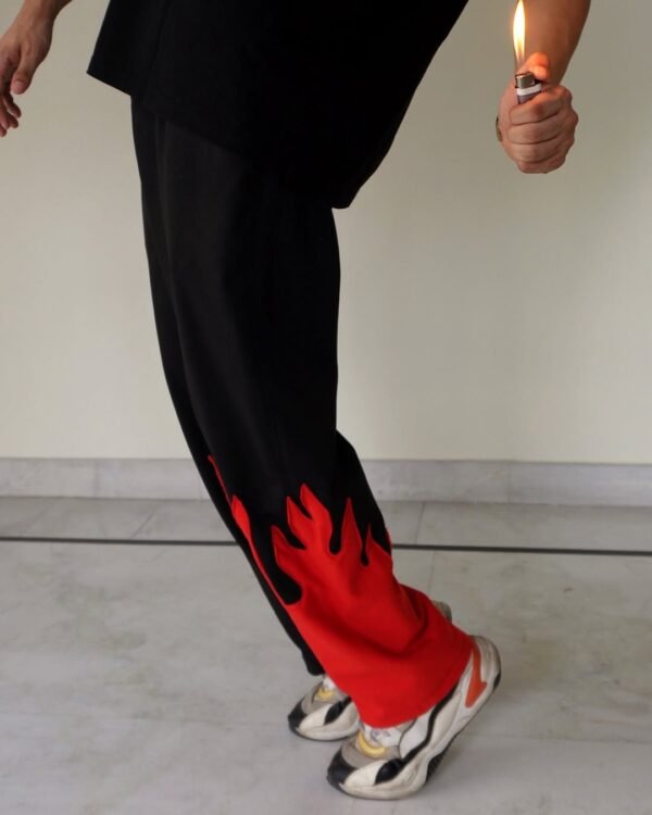 Side view of Red Fire Flame Kick Straight Baggy Track Pant by The Drip Soul showing detailed red flame graphic and relaxed silhouette.