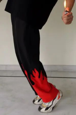 Side view of Red Fire Flame Kick Straight Baggy Track Pant by The Drip Soul showing detailed red flame graphic and relaxed silhouette.