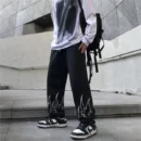 Model wearing The Drip Soul Flame Pant with bold red flame print and baggy streetwear fit.