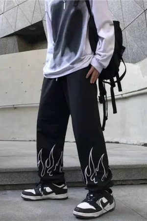 Model wearing The Drip Soul Flame Pant with bold red flame print and baggy streetwear fit.