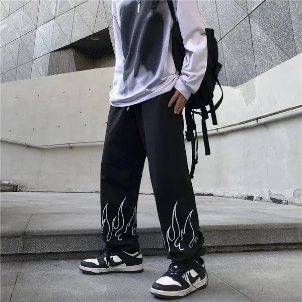 Model wearing The Drip Soul Flame Pant with bold red flame print and baggy streetwear fit.